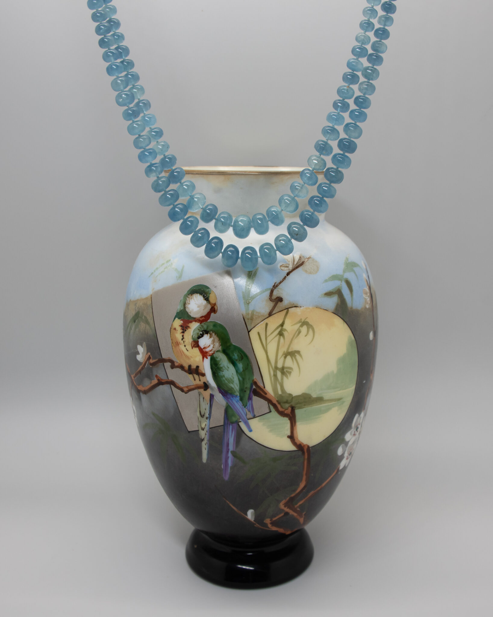 Moss Aquamarine double strand beaded necklace photographed with opaline vase handprinted with parrots