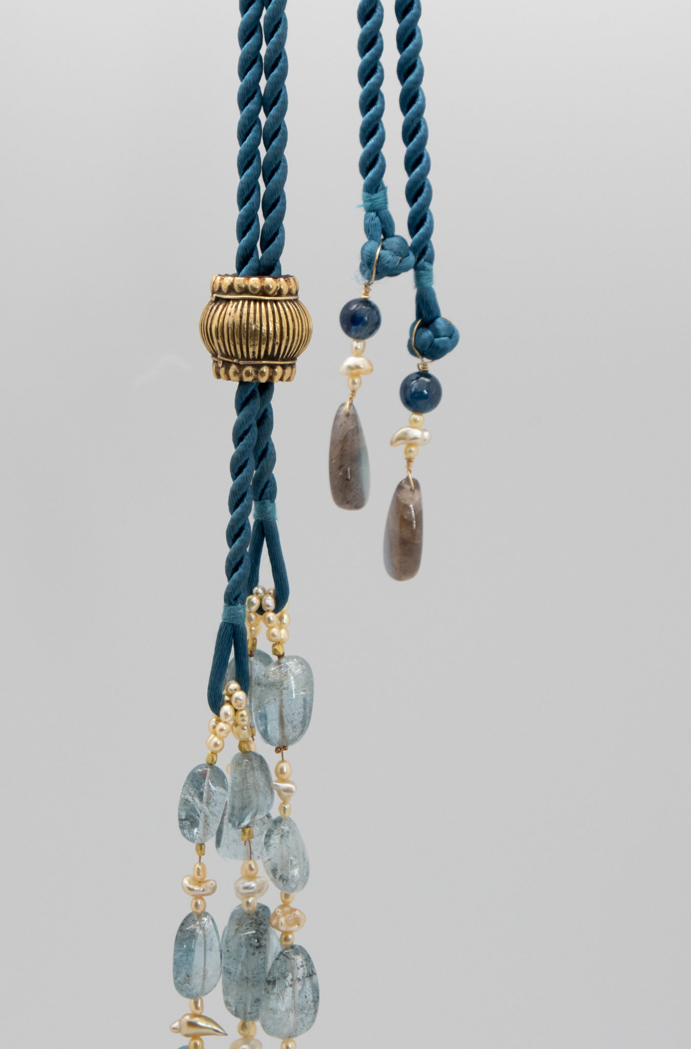 dressmaker details on this aquamarine crystal necklace showing silk cords, pearl loops and tassel detail