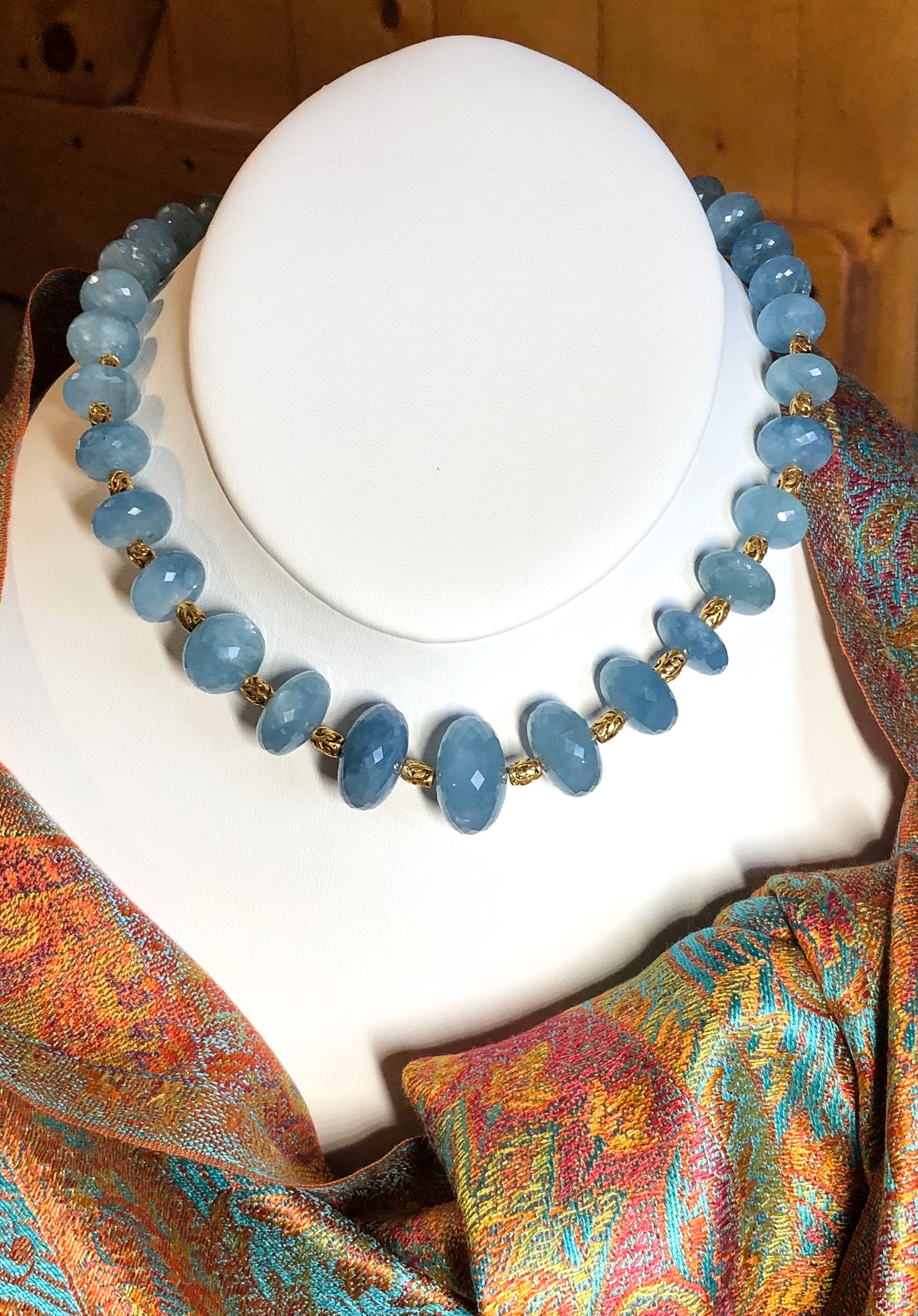 Opaque faceted aquamarine rondelles spaced with 18K gold barrel-shaped beads, shown with an orange and blue silk passim scarf