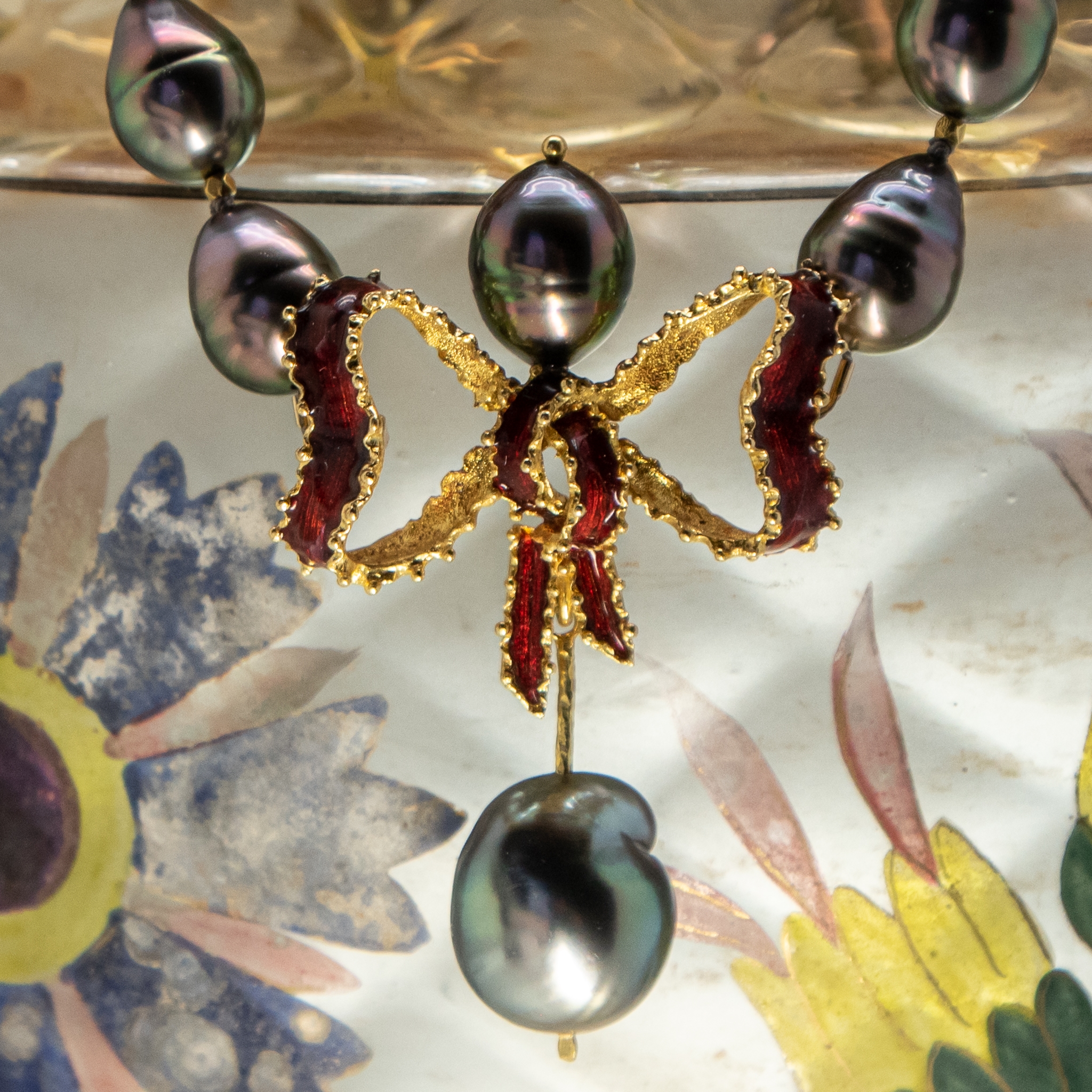 Close-up photo of Italian 18K gold enamel bow with Tahitian pearls necklace