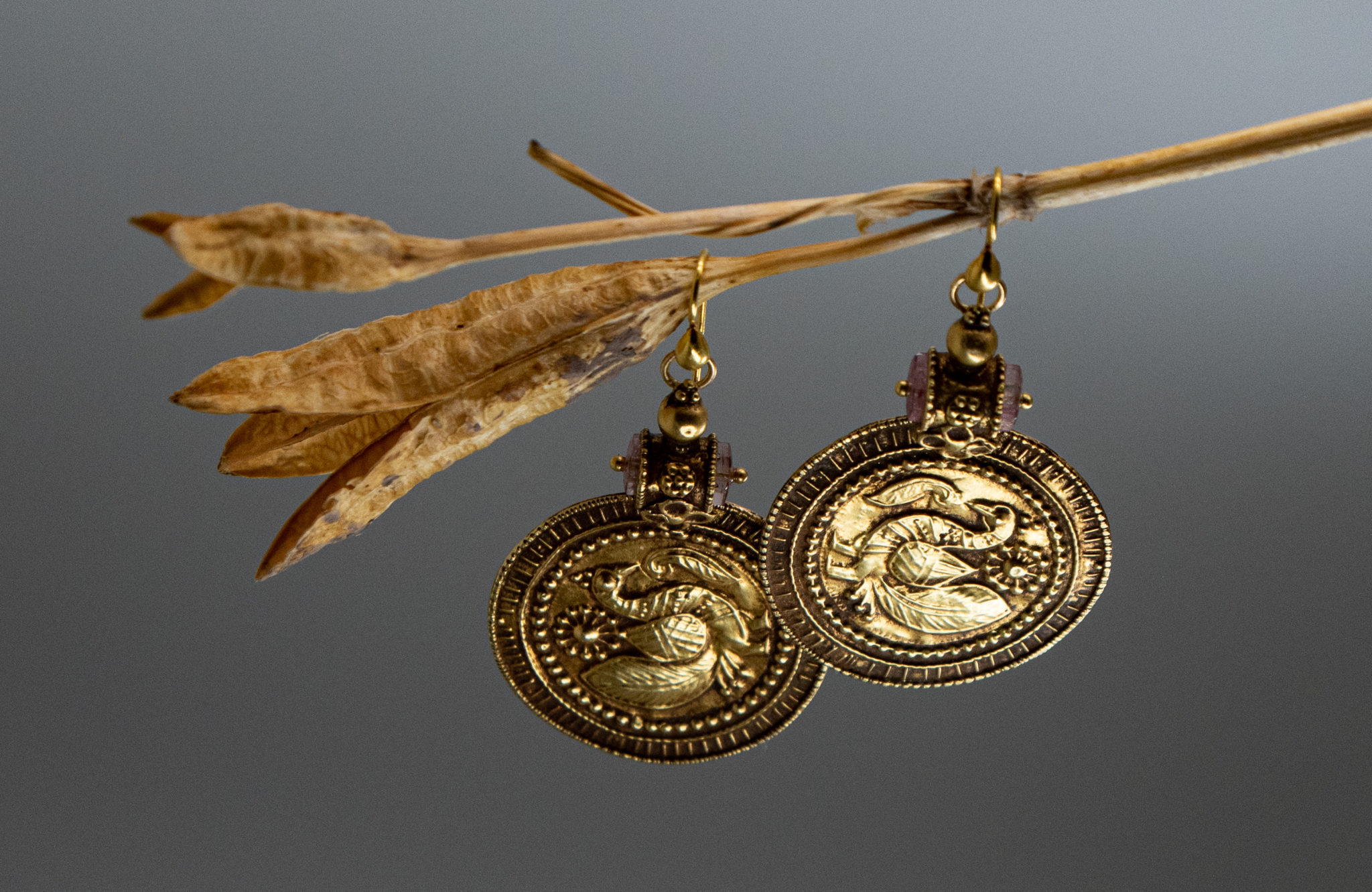view of Antique India embossed medallion earrings with a peacock motif and pink tourmaline accents