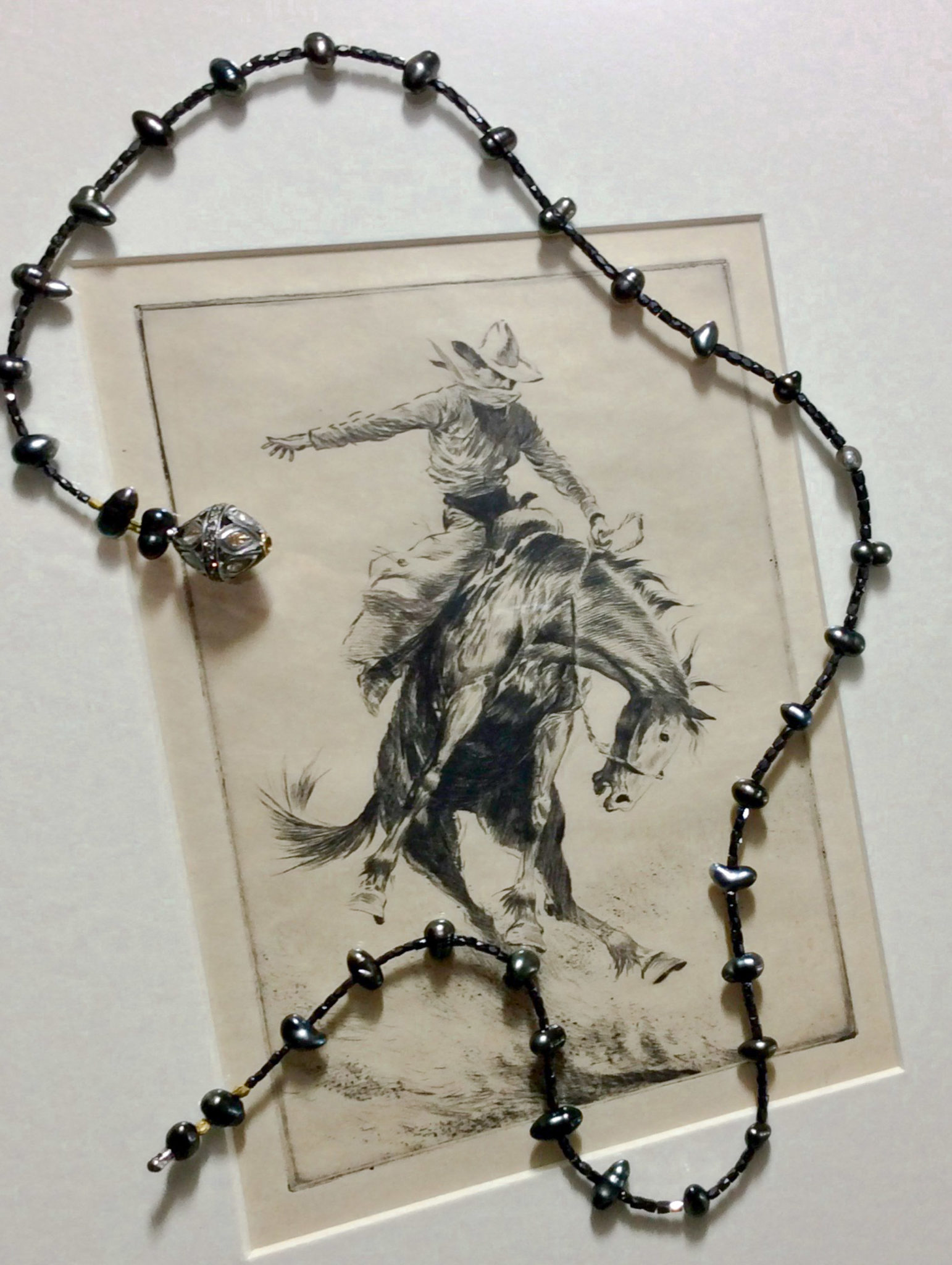 Black diamond and Tahitian pearl necklace shown on etching of a cowboy