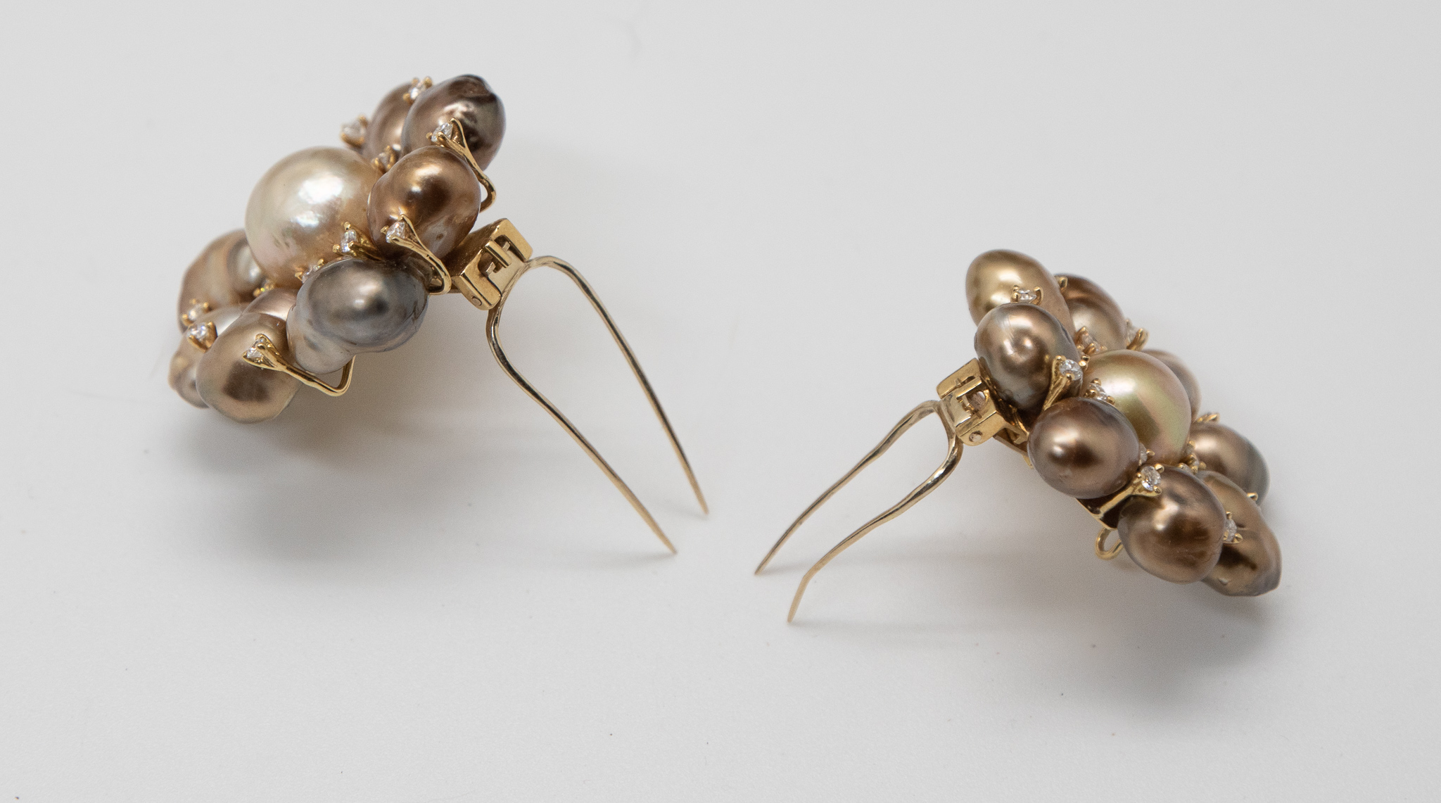 A pair of Tahitian pearl and diamond brooches showing the pin mechanism