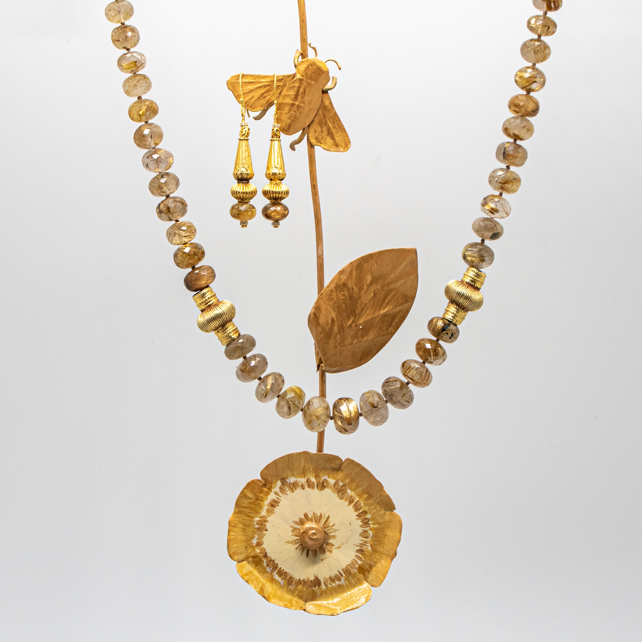 Rutilated Quartz necklace with matching earrings shown with handmade metal flower and moth