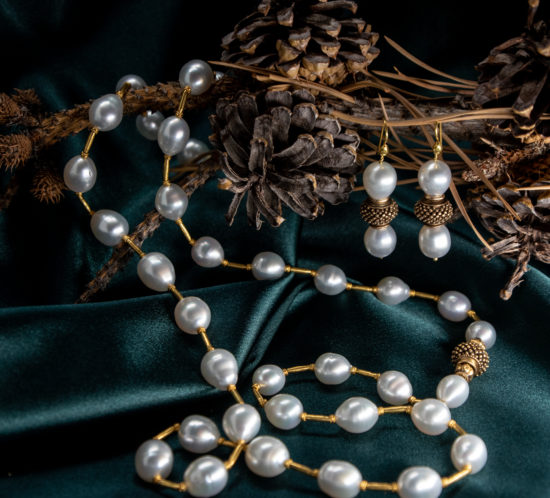 South Sea Pearls necklace with 18K gold spacers photographed on dark green silk with pinecones