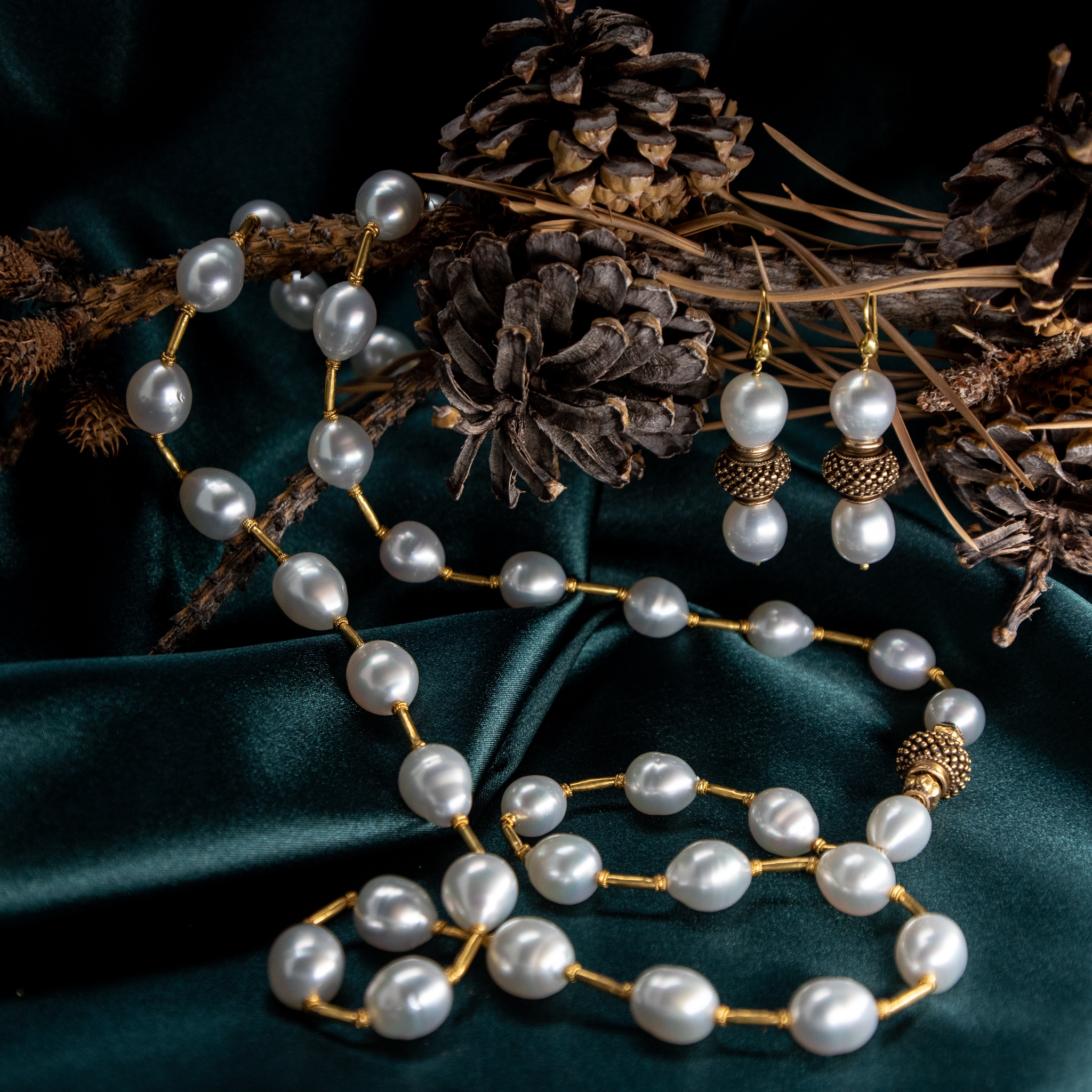 South Sea Pearls necklace with 18K gold spacers photographed on dark green silk with pinecones