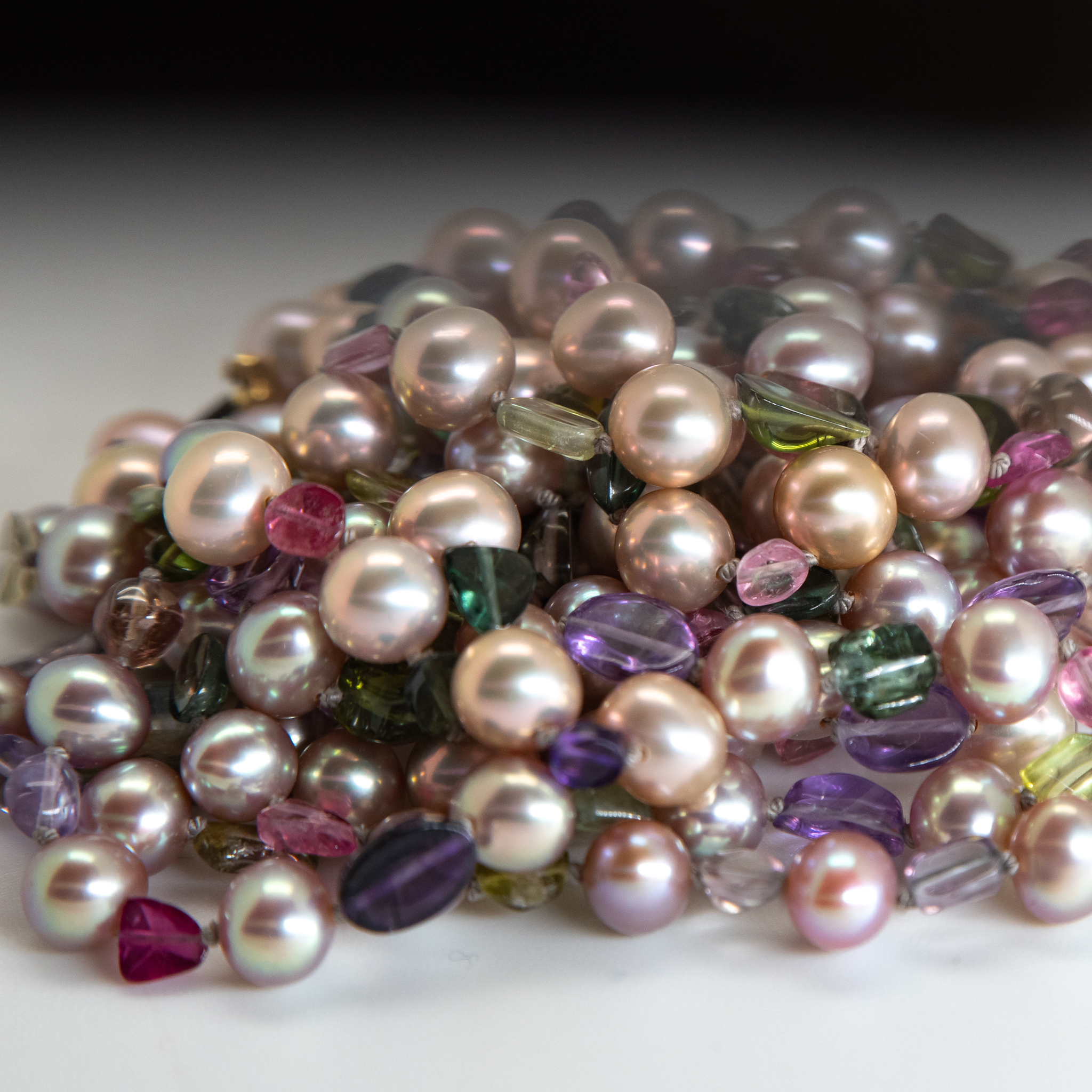 closeup of freshwater pearls and tourmaline cabochons necklace showing hand knotting