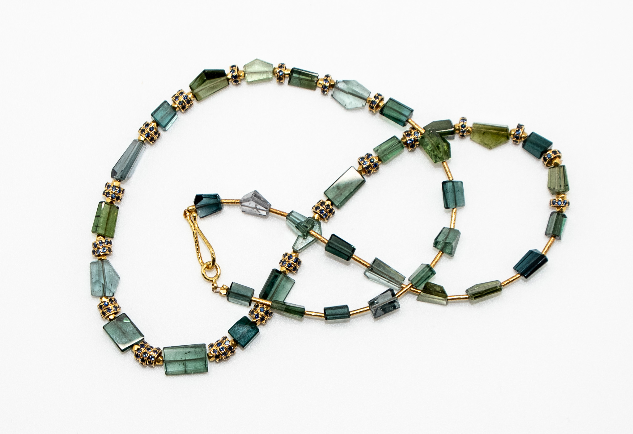 Green polished sliced crystals of tourmaline spaced with 18K gold and sapphire rondelle beads and 18K hook & ey clasp